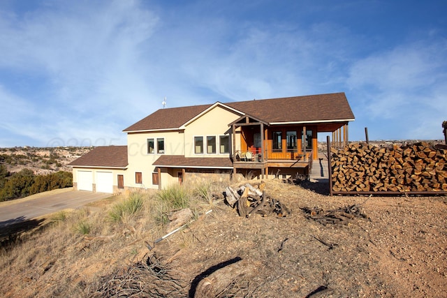 view of front of property featuring covered porch, driveway, a garage, a shingled roof, and stucco siding