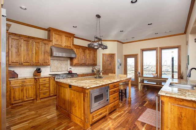 kitchen with ventilation hood, stainless steel appliances, brown cabinets, and a sink