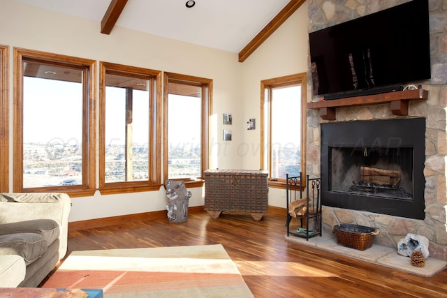 living area with baseboards, vaulted ceiling with beams, a fireplace, and wood finished floors
