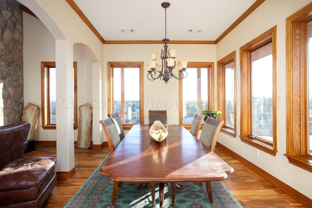dining space featuring arched walkways, a notable chandelier, visible vents, and wood finished floors