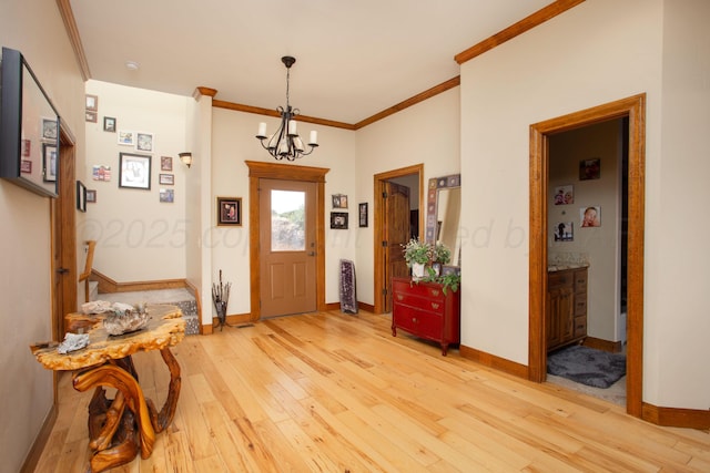 entrance foyer with an inviting chandelier, light wood-style flooring, crown molding, and baseboards