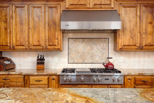 kitchen featuring decorative backsplash, stainless steel gas cooktop, brown cabinets, and range hood