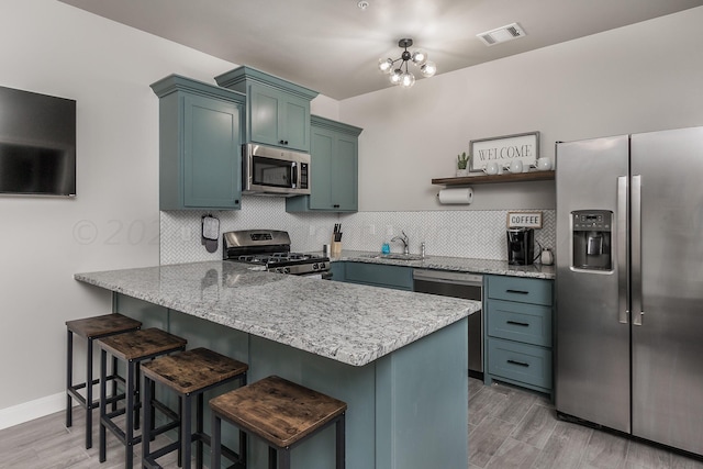 kitchen featuring kitchen peninsula, stainless steel appliances, tasteful backsplash, and a breakfast bar