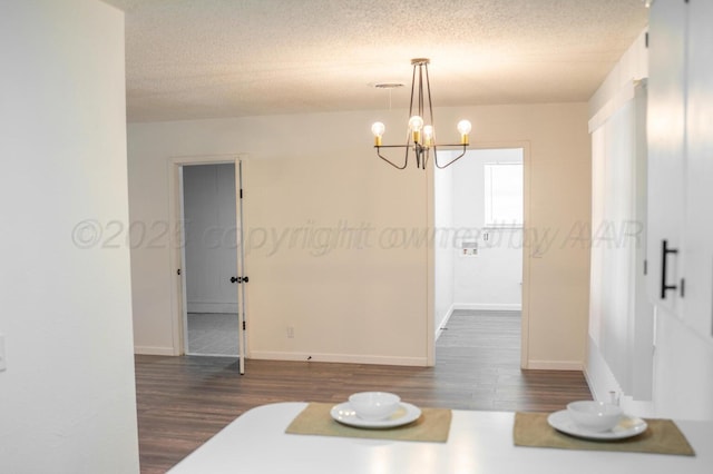 interior space with a textured ceiling, an inviting chandelier, dark wood finished floors, and baseboards