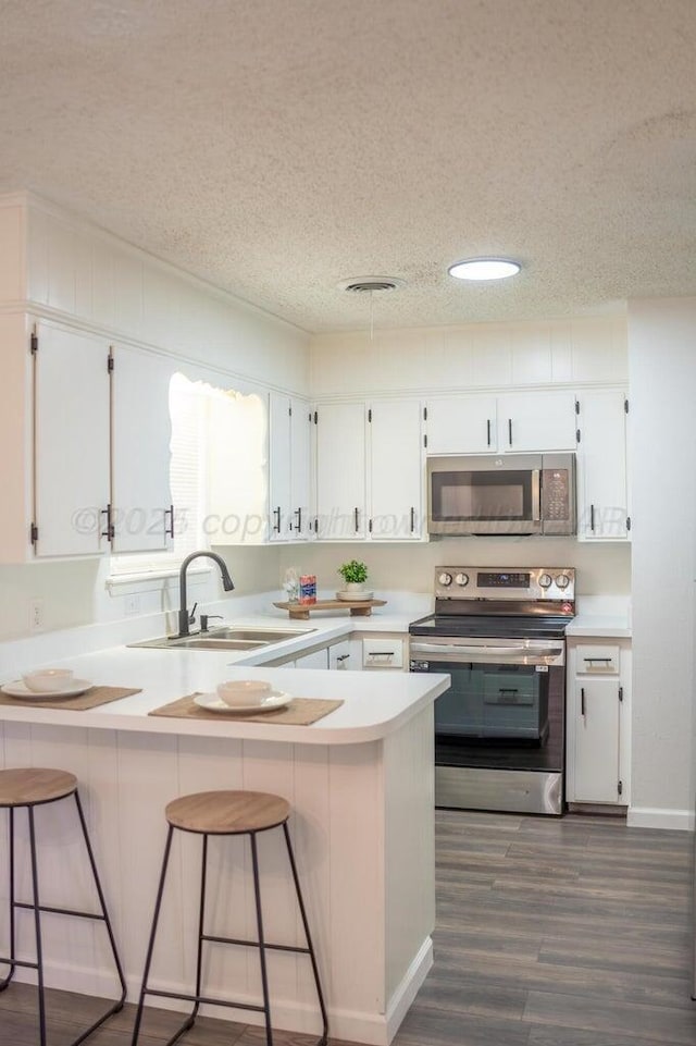 kitchen with visible vents, white cabinets, a peninsula, stainless steel appliances, and light countertops