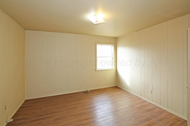 empty room featuring wooden walls and hardwood / wood-style floors