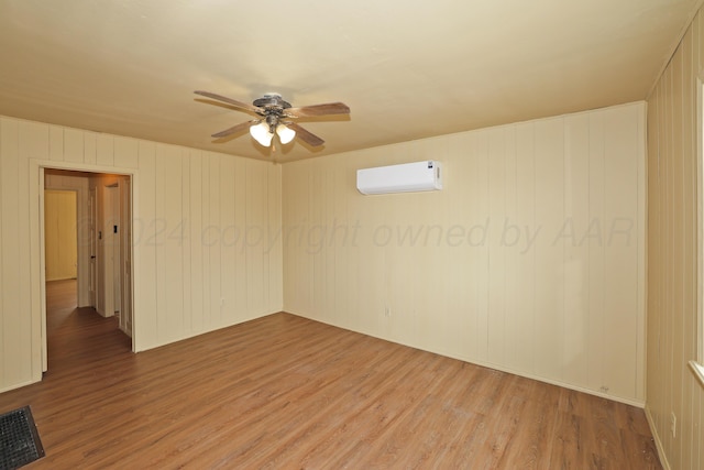 spare room with wooden walls, ceiling fan, wood-type flooring, and a wall unit AC