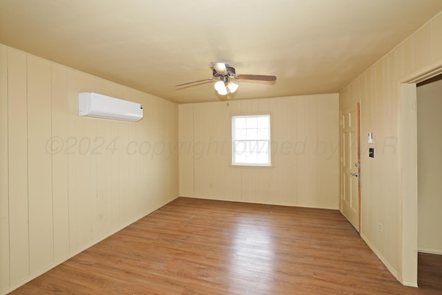 spare room with a wall mounted AC, ceiling fan, and light hardwood / wood-style floors