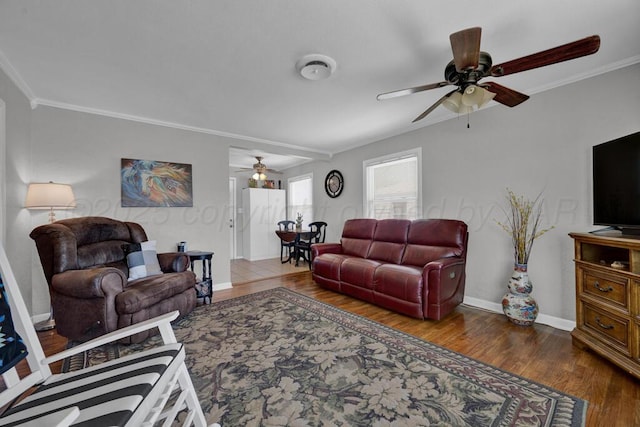 living area featuring ornamental molding, baseboards, wood finished floors, and ceiling fan