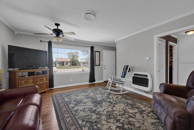 living area featuring baseboards, heating unit, wood finished floors, a ceiling fan, and crown molding