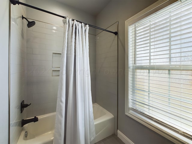 full bath with shower / bath combo with shower curtain and baseboards