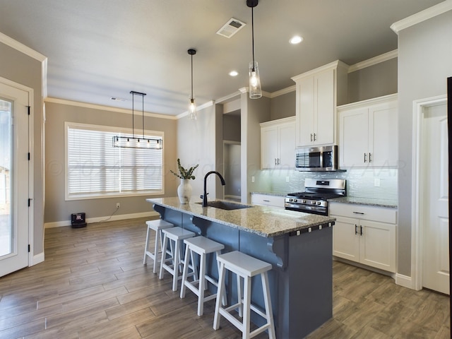kitchen with stainless steel appliances, visible vents, a sink, and crown molding