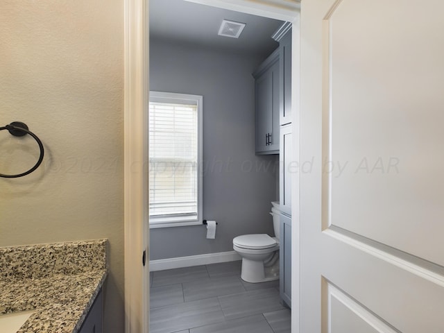 bathroom with vanity, baseboards, tile patterned flooring, toilet, and visible vents