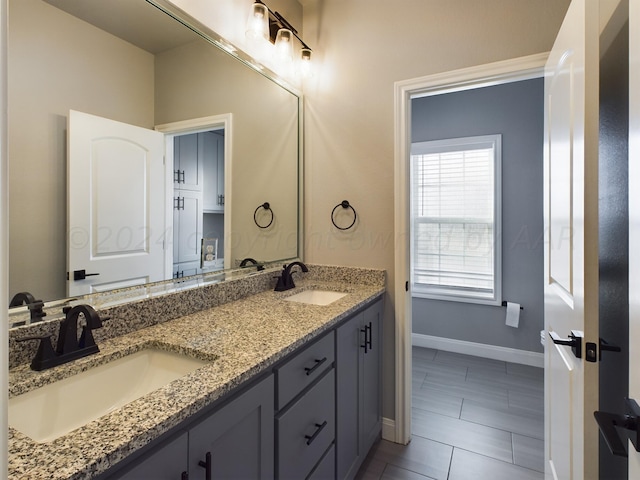 full bathroom featuring a sink, baseboards, and double vanity