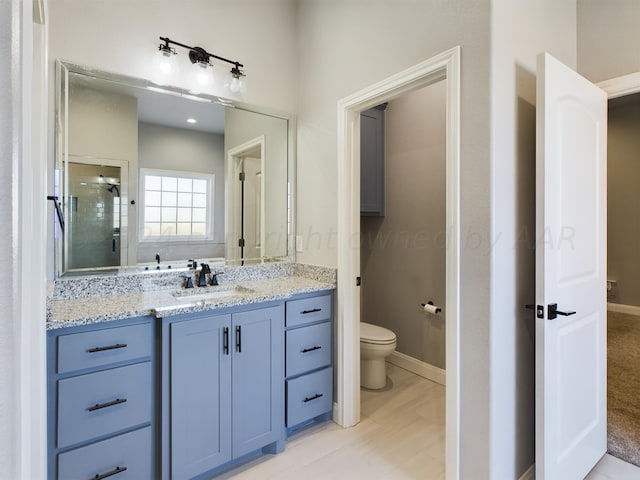 full bathroom with toilet, a stall shower, baseboards, and vanity