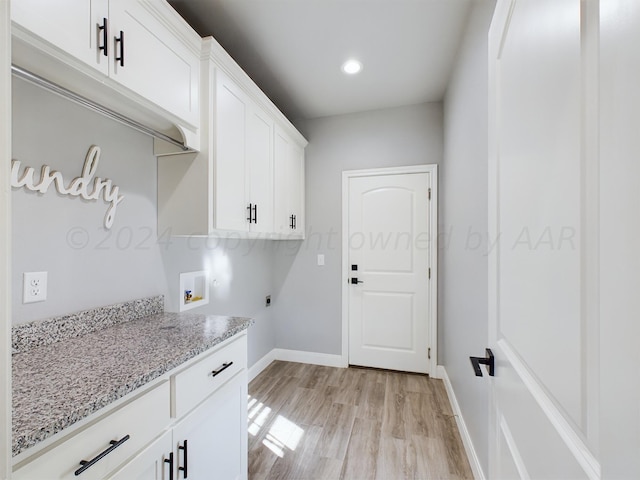 clothes washing area featuring electric dryer hookup, light wood-style flooring, washer hookup, baseboards, and cabinet space