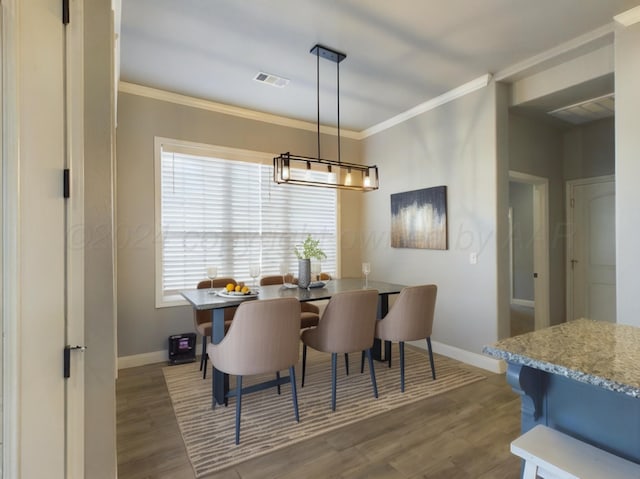 dining space featuring a notable chandelier, baseboards, ornamental molding, visible vents, and wood finished floors