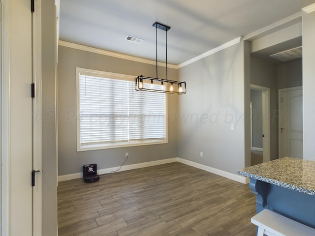 unfurnished dining area featuring an inviting chandelier, visible vents, crown molding, and wood finished floors
