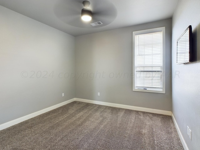 unfurnished room featuring visible vents, dark carpet, ceiling fan, and baseboards