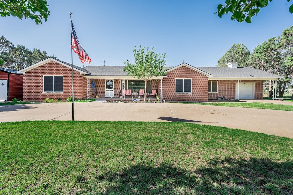 ranch-style home featuring a garage, a front lawn, and covered porch