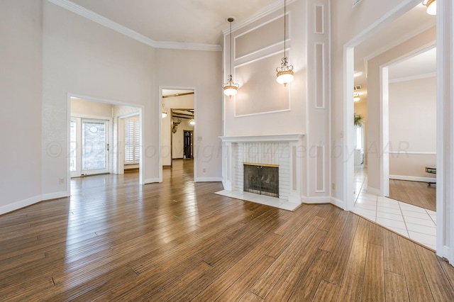 unfurnished living room featuring a brick fireplace, hardwood / wood-style flooring, and ornamental molding