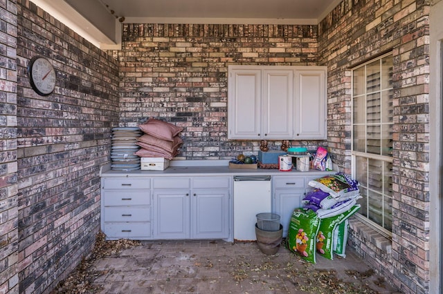 kitchen with white cabinetry and brick wall