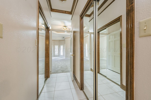 hallway with light tile patterned floors and crown molding