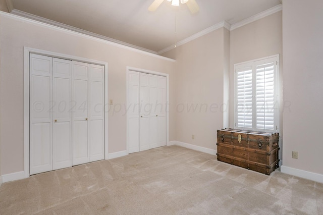 unfurnished bedroom featuring multiple closets, light colored carpet, ceiling fan, and crown molding