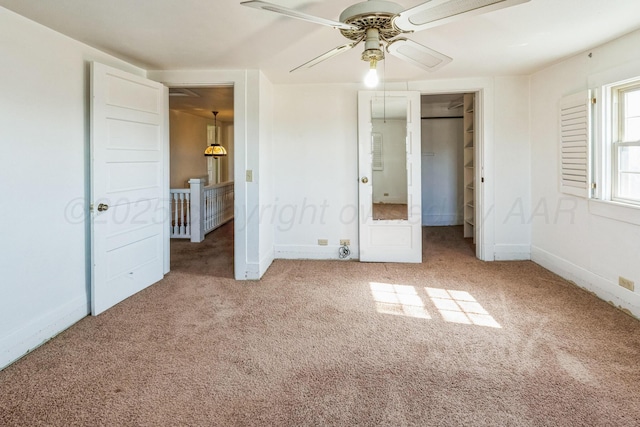 unfurnished bedroom featuring a spacious closet, a closet, ceiling fan, and carpet flooring