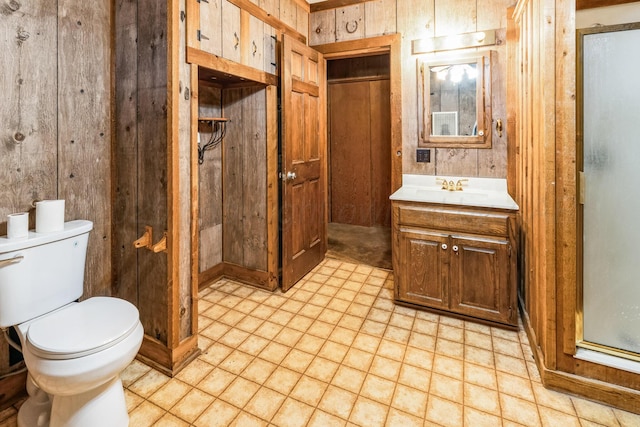 bathroom featuring vanity, toilet, and wood walls