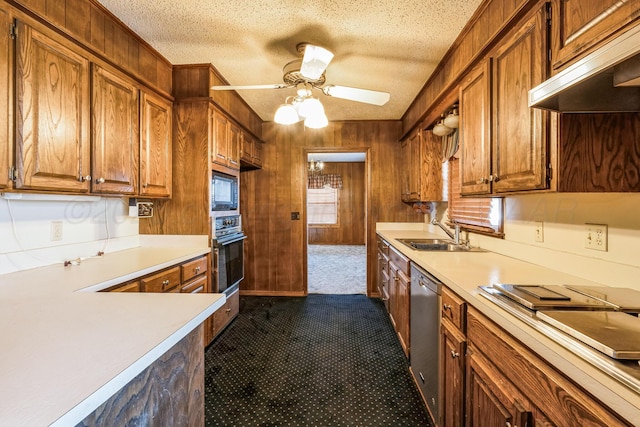 kitchen with wooden walls, sink, a textured ceiling, and black appliances