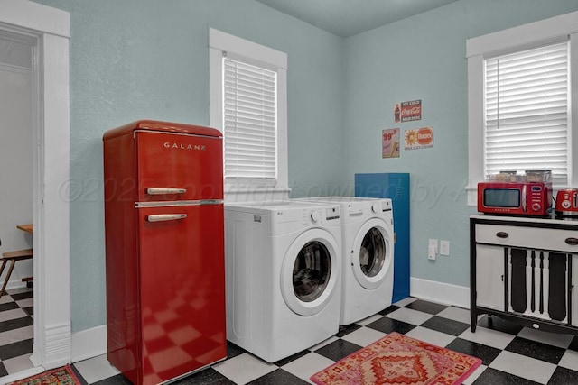 clothes washing area with tile patterned floors, washer and clothes dryer, and baseboards