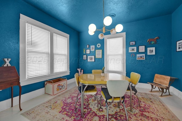 dining room featuring a chandelier, plenty of natural light, a textured ceiling, and baseboards