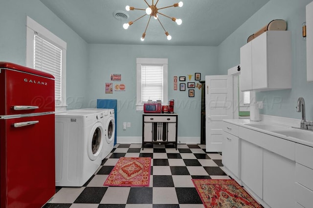 laundry room featuring washer and clothes dryer, dark flooring, a chandelier, and baseboards