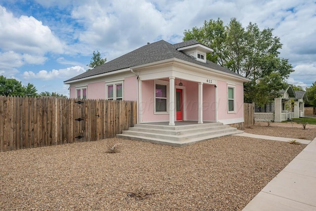 bungalow featuring a porch, fence, and roof with shingles