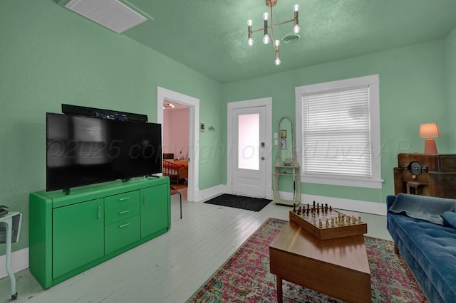 living room featuring wood finished floors, a chandelier, a textured ceiling, and baseboards