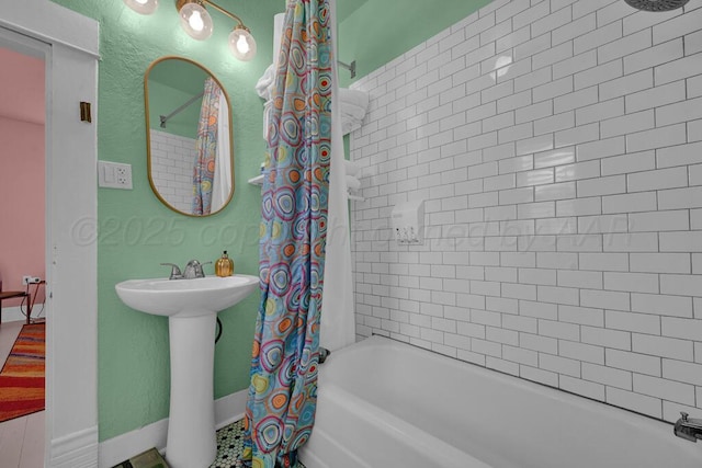 full bath with shower / bath combination with curtain, baseboards, and a sink