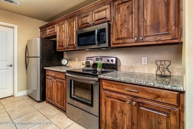 kitchen featuring light tile patterned flooring, light stone counters, and appliances with stainless steel finishes