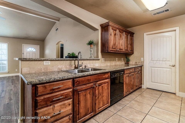 kitchen featuring sink, light tile patterned floors, lofted ceiling with beams, dark stone countertops, and dishwasher