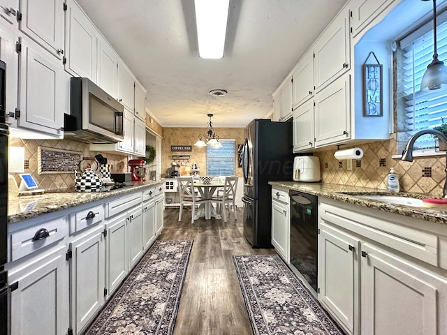 1417 Bluebonnet St, Borger, TX 79007 - kitchen with a sink, black appliances, white cabinets, dark wood finished floors, and tasteful backsplash