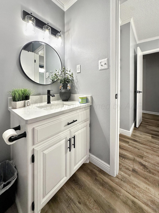 1417 Bluebonnet St, Borger, TX 79007 - bathroom with crown molding, wood finished floors, baseboards, vanity, and a textured ceiling