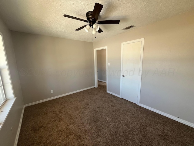 unfurnished bedroom with a textured ceiling, ceiling fan, and dark colored carpet