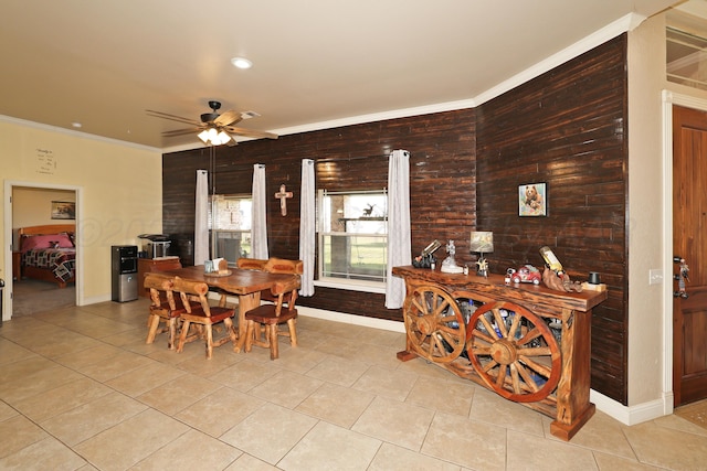 tiled dining room with ceiling fan, wood walls, and ornamental molding