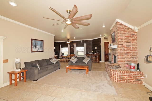 living room with crown molding, light tile patterned flooring, a fireplace, and ceiling fan