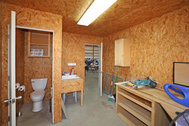 bathroom with sink, toilet, and concrete floors