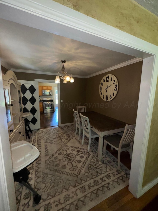 dining room with ornamental molding, a chandelier, and wood finished floors