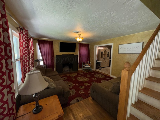 living area featuring a textured ceiling, stairs, and a fireplace