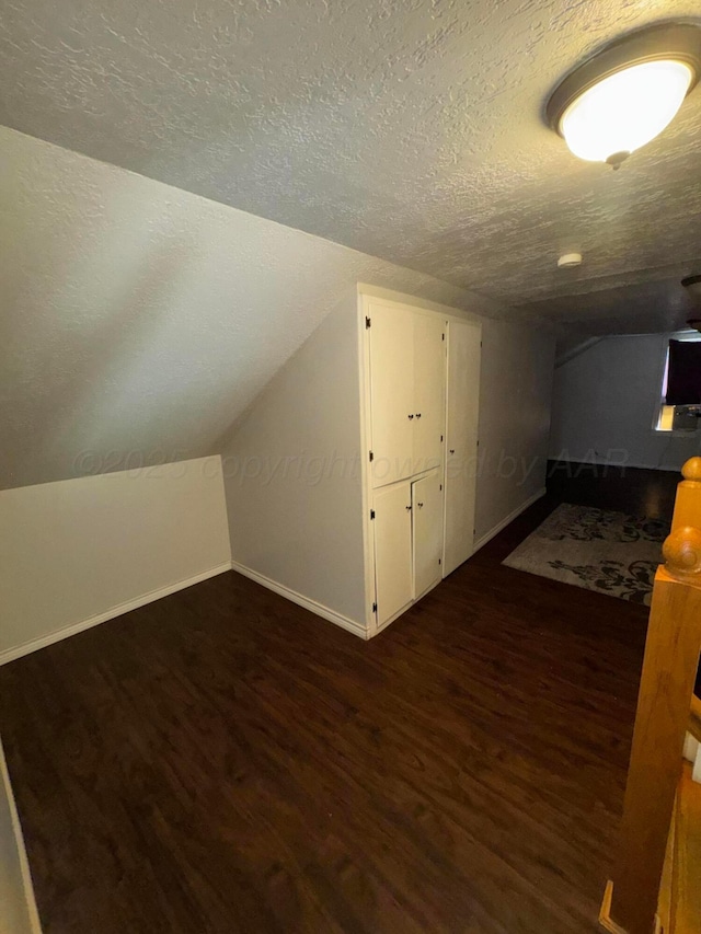 additional living space with wood finished floors, baseboards, a textured ceiling, and lofted ceiling