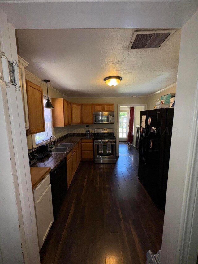 kitchen with black appliances, a sink, dark wood-style floors, dark countertops, and hanging light fixtures
