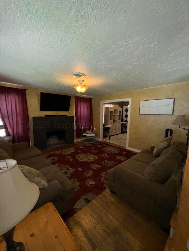 living room featuring a textured ceiling and a fireplace